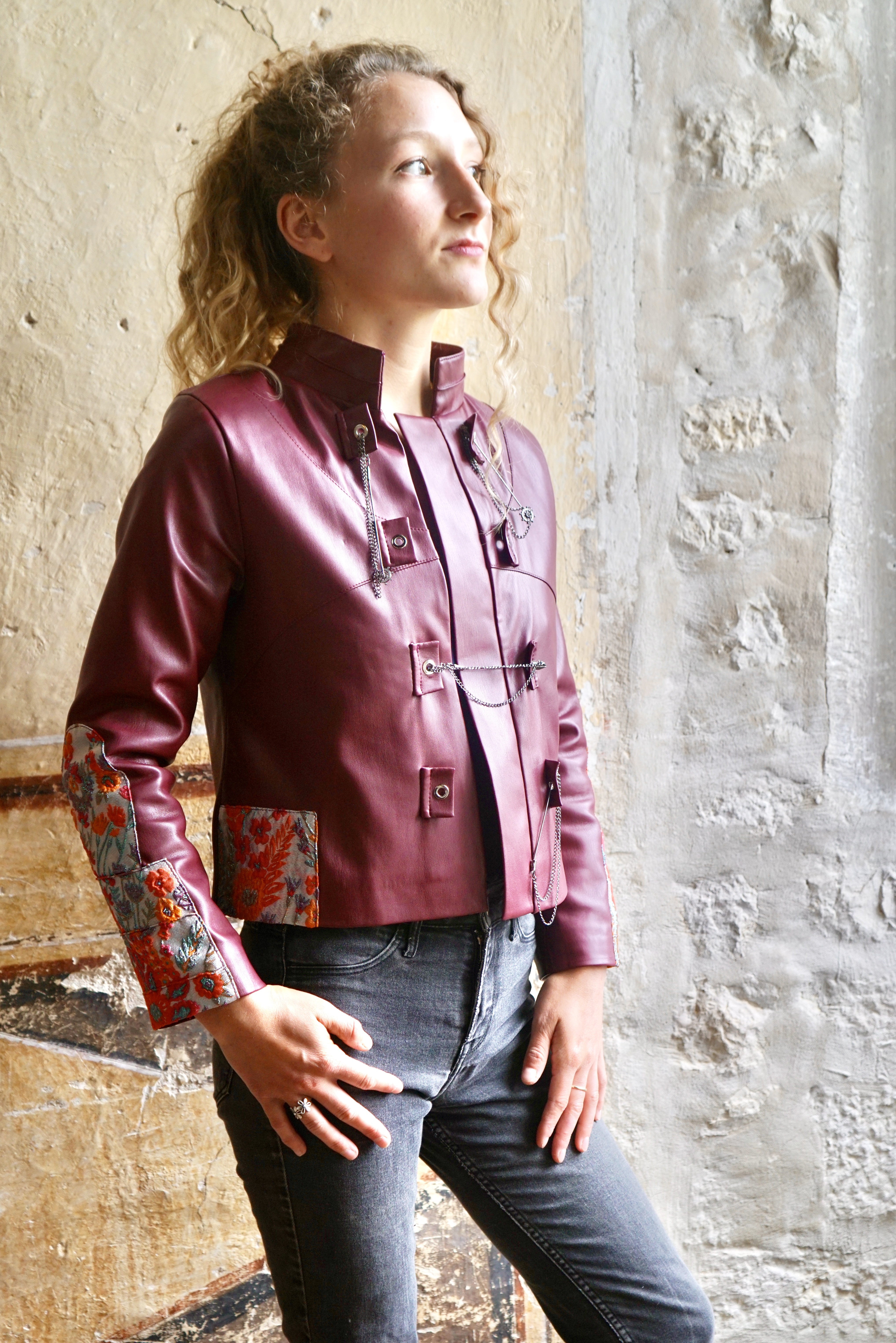A model in a red leather jacket with embroidered patches and metal fastenings